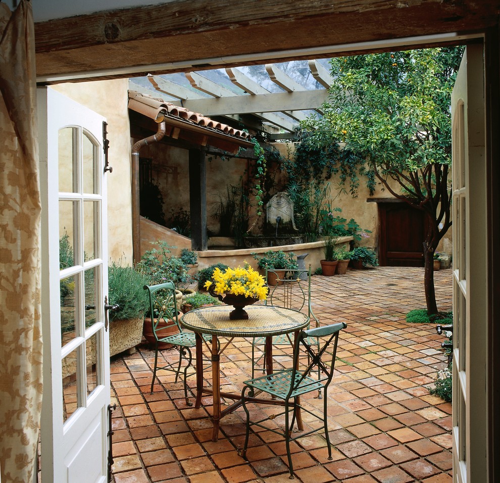 Esempio di un patio o portico mediterraneo in cortile con pavimentazioni in mattoni