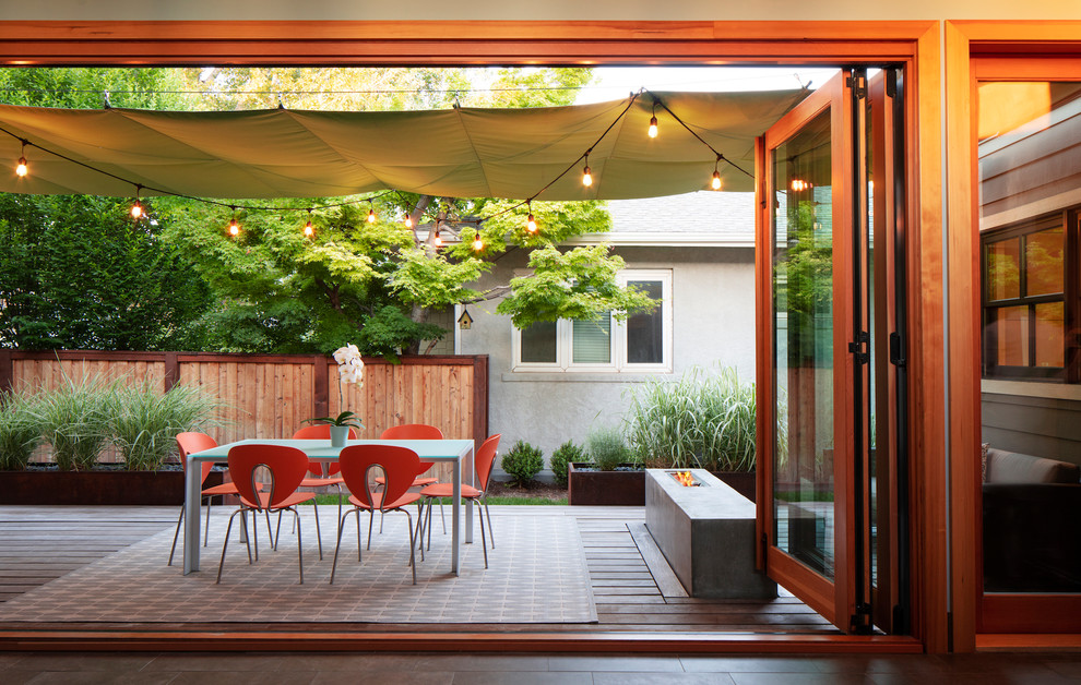 Diseño de patio contemporáneo en patio trasero con brasero, entablado y toldo
