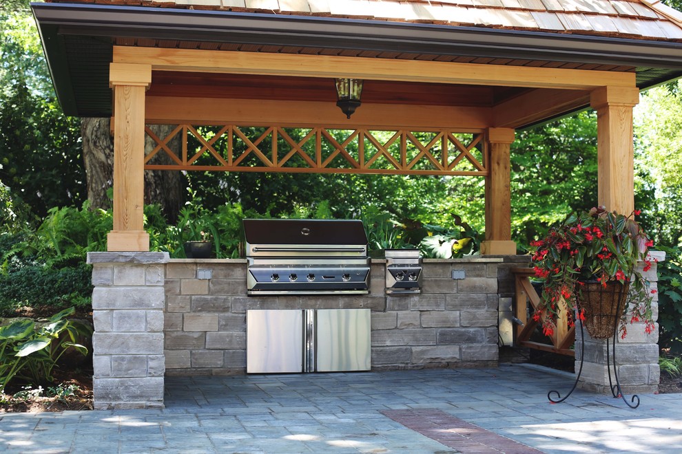 Diseño de patio clásico de tamaño medio en patio trasero con cocina exterior, adoquines de hormigón y cenador