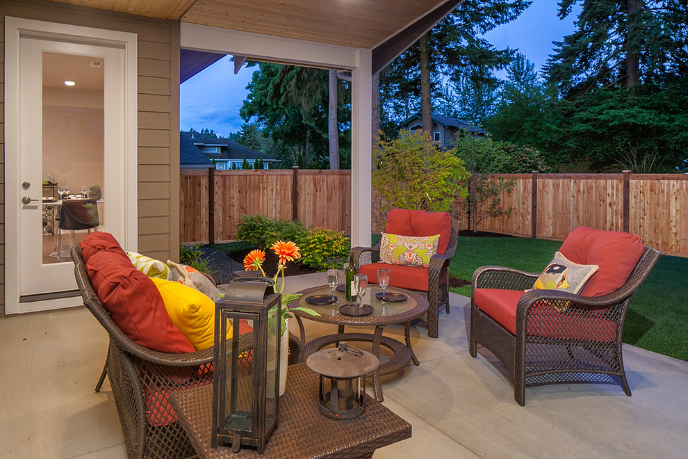 This is an example of a traditional back patio in Seattle with concrete slabs and a roof extension.