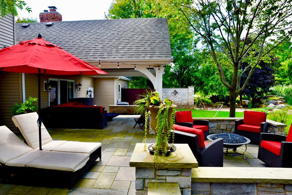 Esempio di un grande patio o portico american style dietro casa con un focolare, cemento stampato e un tetto a sbalzo
