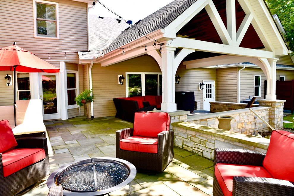 Esempio di un grande patio o portico stile americano dietro casa con un focolare, cemento stampato e un tetto a sbalzo