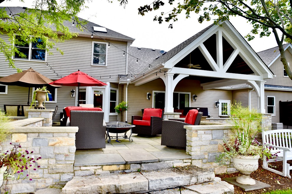 Esempio di un grande patio o portico stile americano dietro casa con un focolare, cemento stampato e un tetto a sbalzo