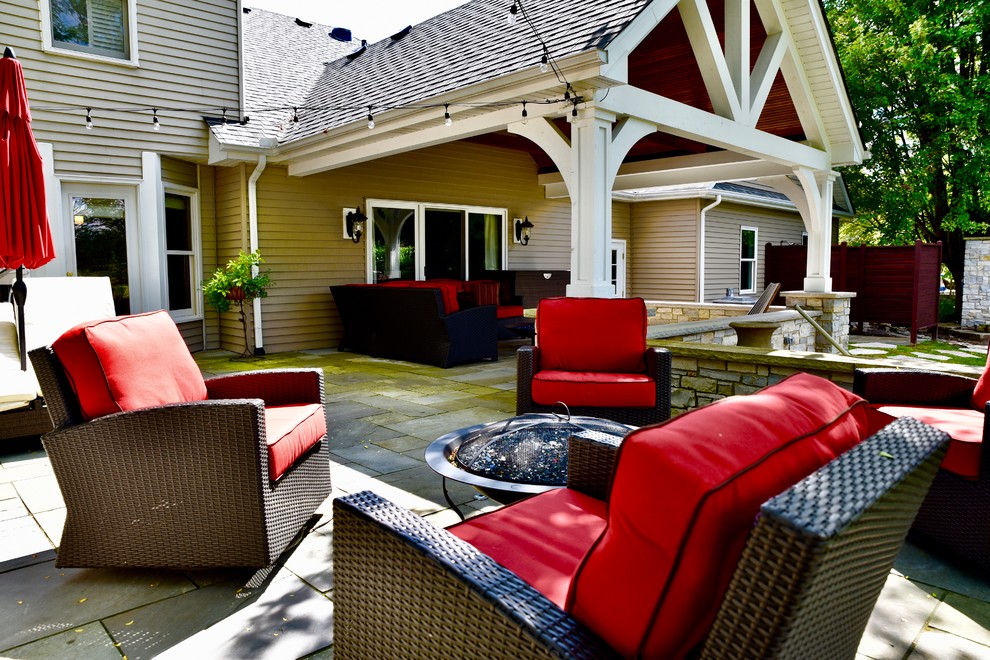 Immagine di un grande patio o portico american style dietro casa con un focolare, cemento stampato e un tetto a sbalzo