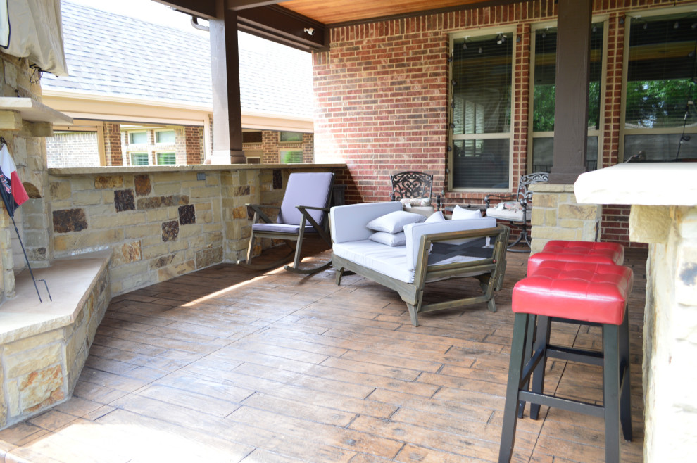 Large eclectic back patio in Dallas with a fireplace, stamped concrete and a roof extension.