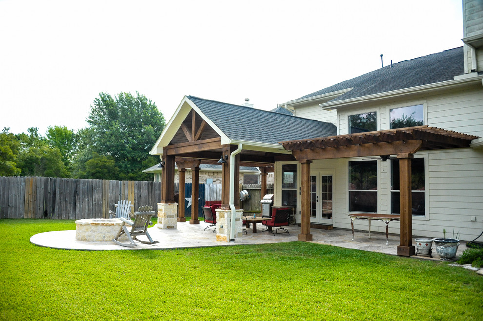 Idee per un patio o portico tradizionale di medie dimensioni e dietro casa con un focolare, cemento stampato e una pergola