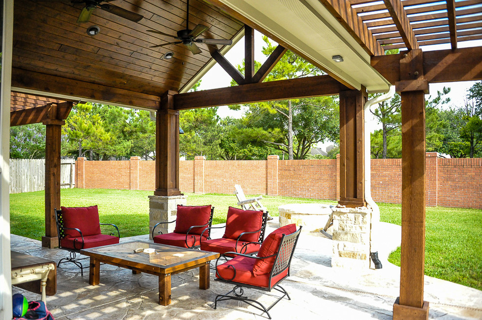 Esempio di un patio o portico classico di medie dimensioni e dietro casa con un focolare, cemento stampato e una pergola