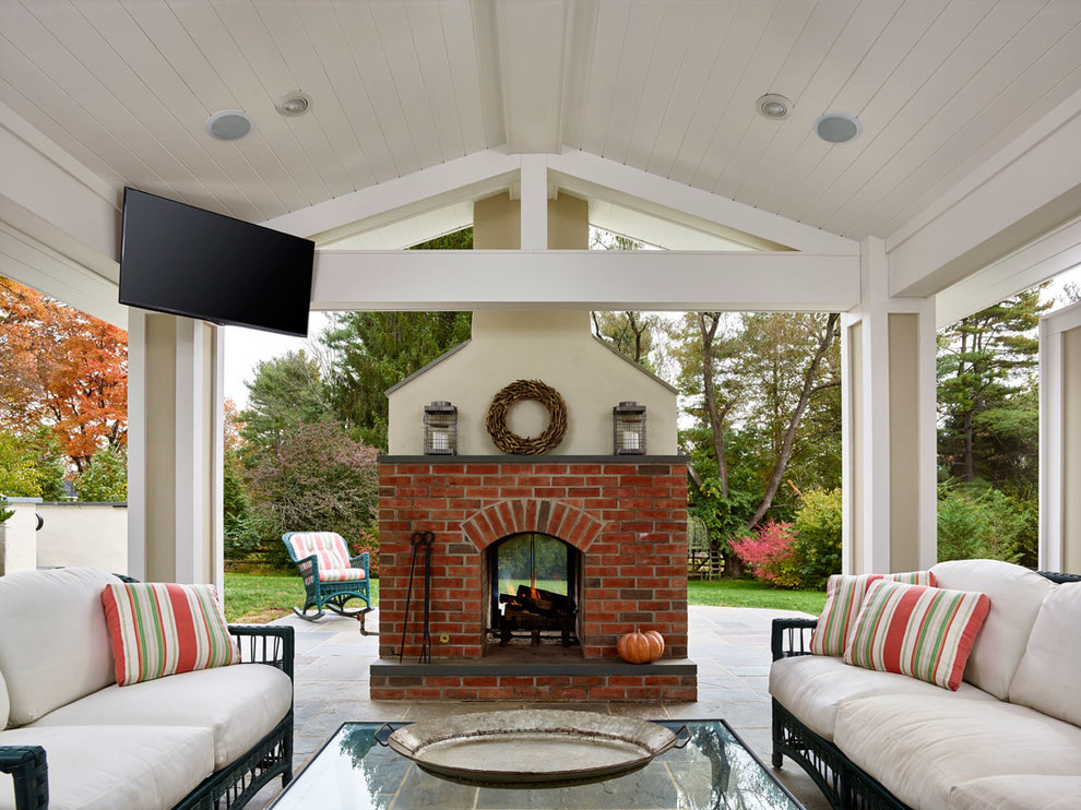 Cette image montre une terrasse arrière traditionnelle de taille moyenne avec un foyer extérieur, des pavés en pierre naturelle et une extension de toiture.