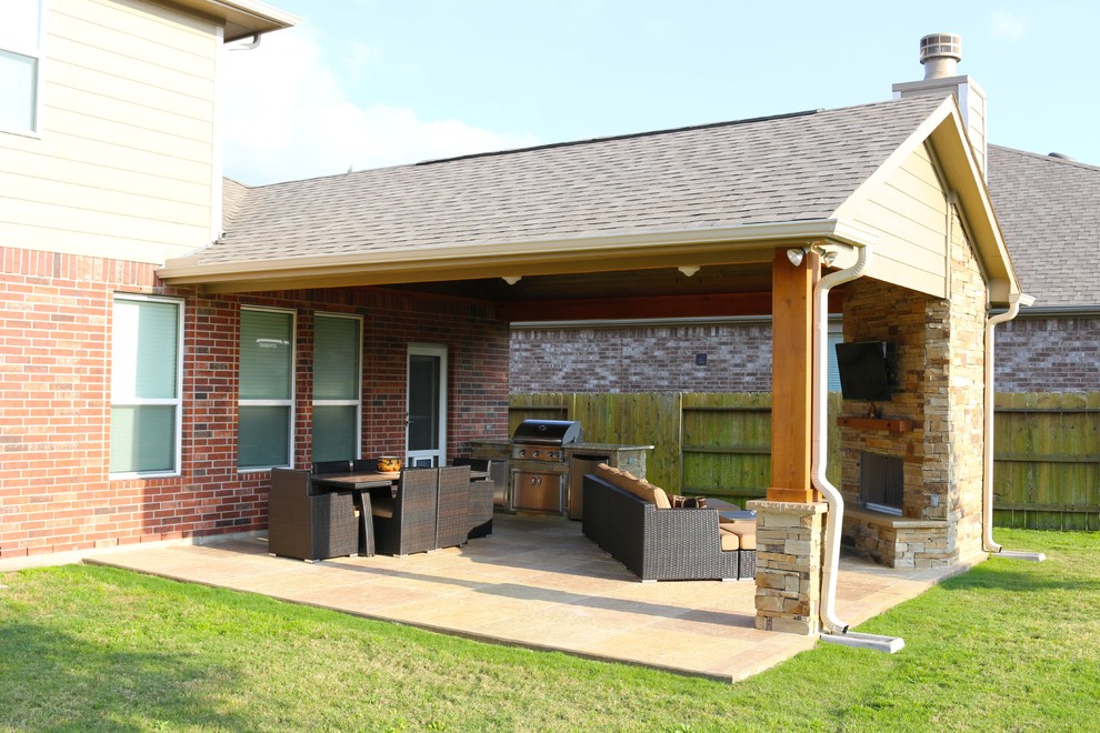 Traditional back patio in Houston with an outdoor kitchen, stamped concrete and a roof extension.