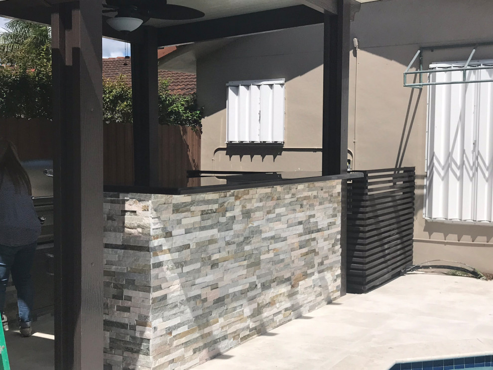 Aménagement d'une petite terrasse arrière contemporaine avec une cuisine d'été, des pavés en pierre naturelle et une pergola.