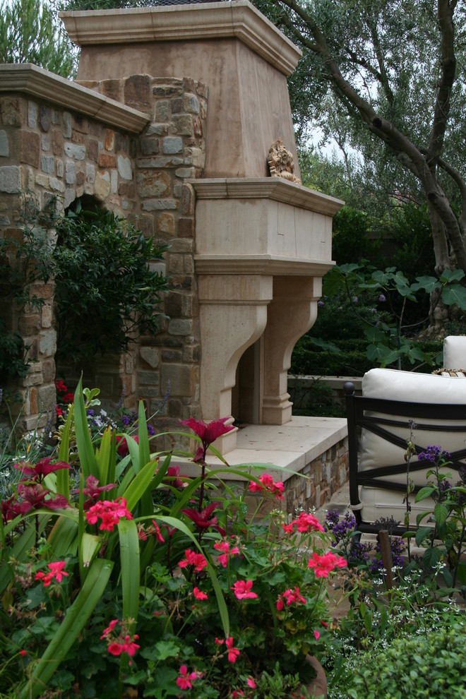Diseño de patio mediterráneo de tamaño medio sin cubierta en patio trasero con brasero y adoquines de piedra natural