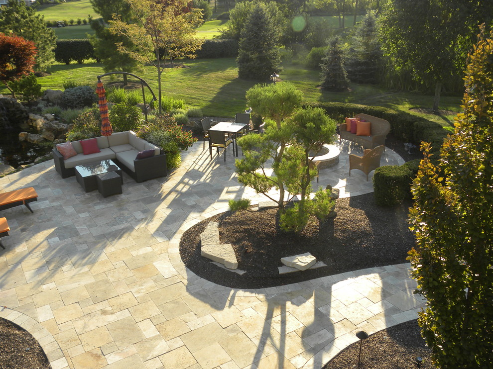 Foto di un ampio patio o portico classico dietro casa con un focolare e pavimentazioni in pietra naturale