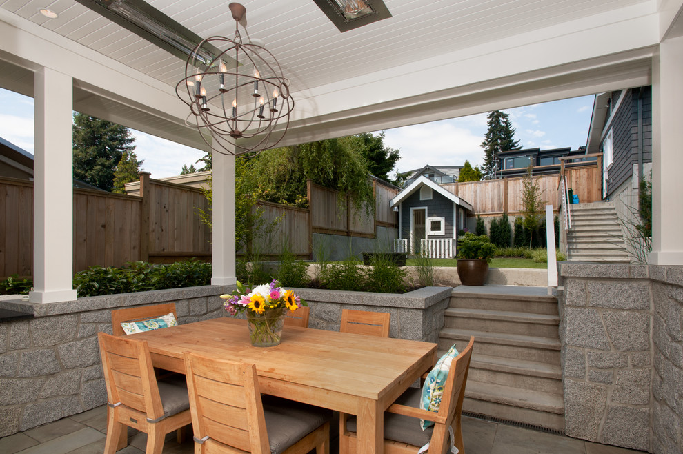 Immagine di un piccolo patio o portico stile americano dietro casa con pavimentazioni in pietra naturale e un tetto a sbalzo