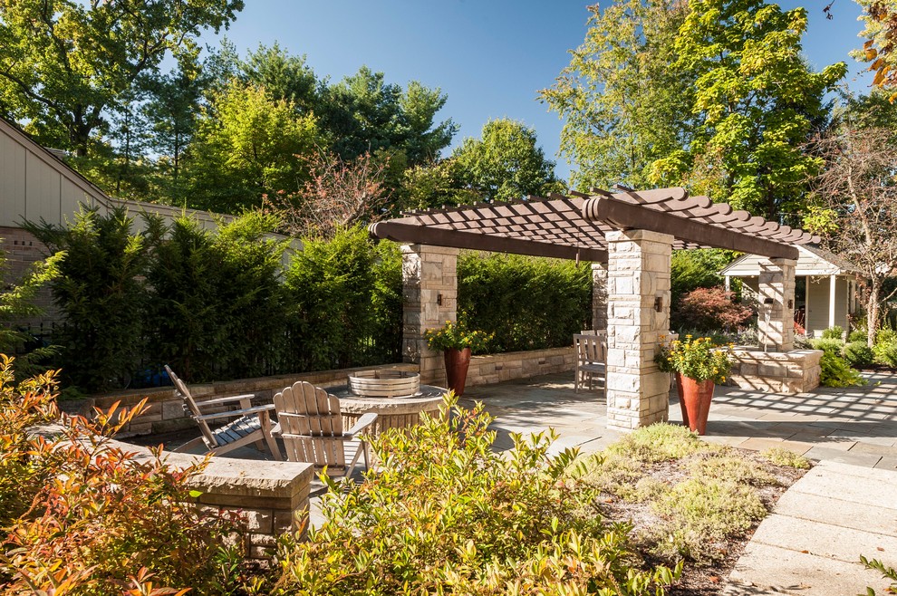 Example of a large country backyard stone patio design in Indianapolis with a fire pit and a pergola