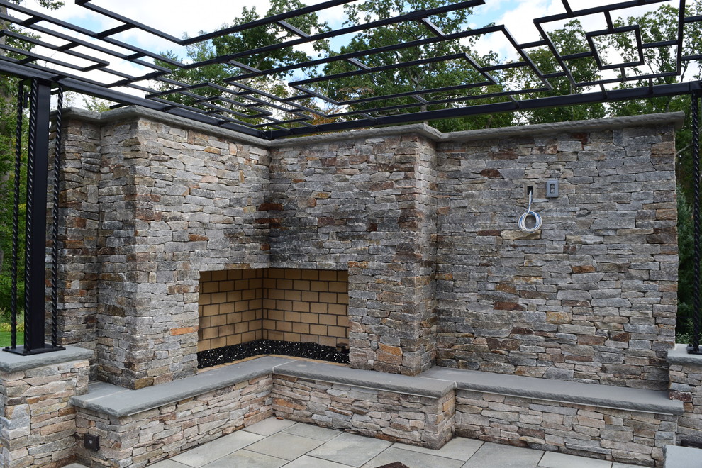 Inspiration for a large modern back patio in New York with a water feature, natural stone paving and a pergola.