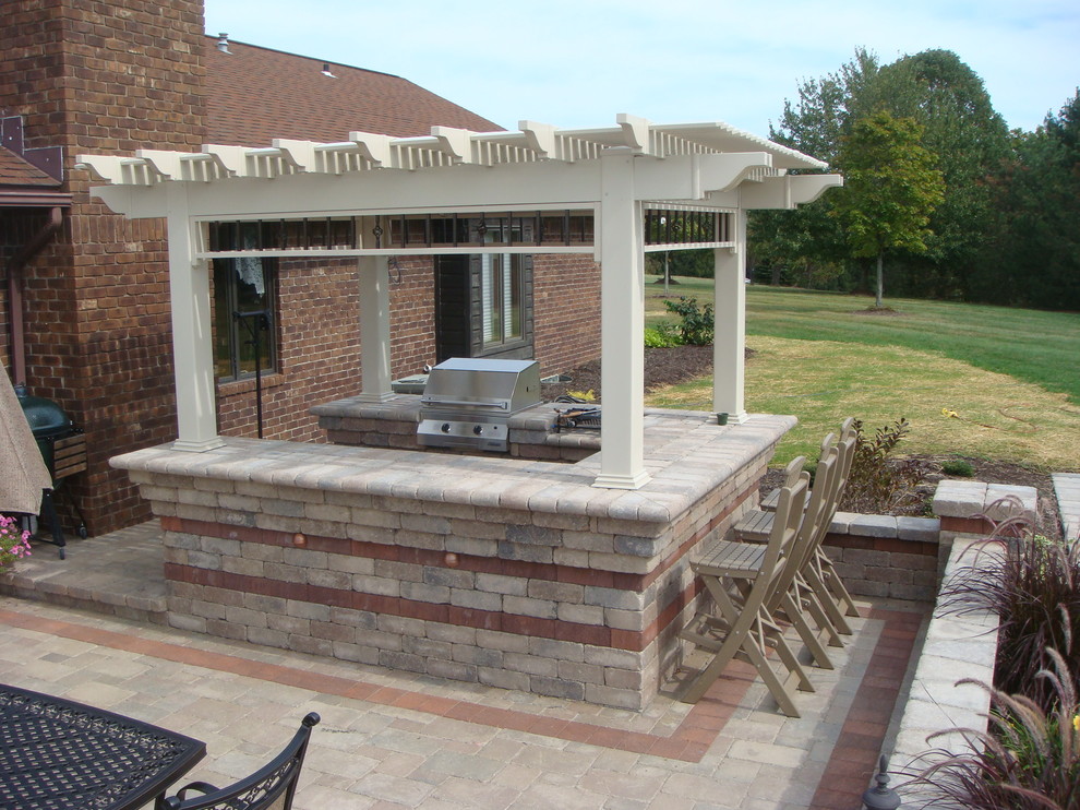 Diseño de patio de estilo americano grande en patio trasero con cocina exterior, adoquines de ladrillo y pérgola