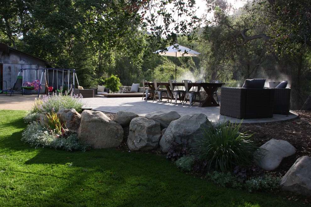 Foto di un grande patio o portico country dietro casa con pavimentazioni in pietra naturale e nessuna copertura