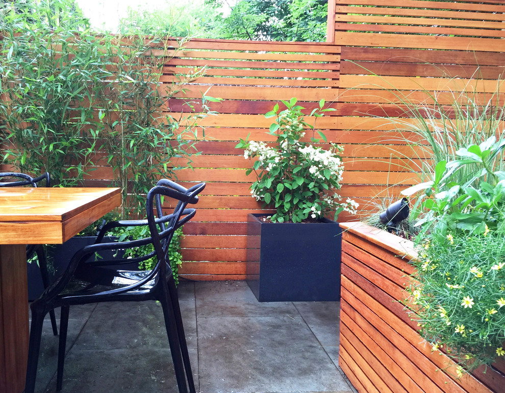 Diseño de patio actual en patio trasero con jardín de macetas y adoquines de piedra natural