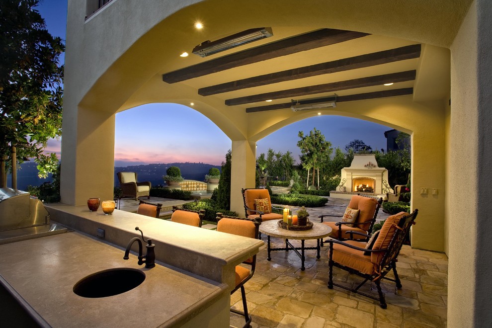 Large tuscan backyard stone patio kitchen photo in Orange County with a gazebo