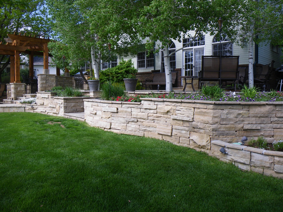 Design ideas for a large rustic back patio in Denver with natural stone paving and a pergola.