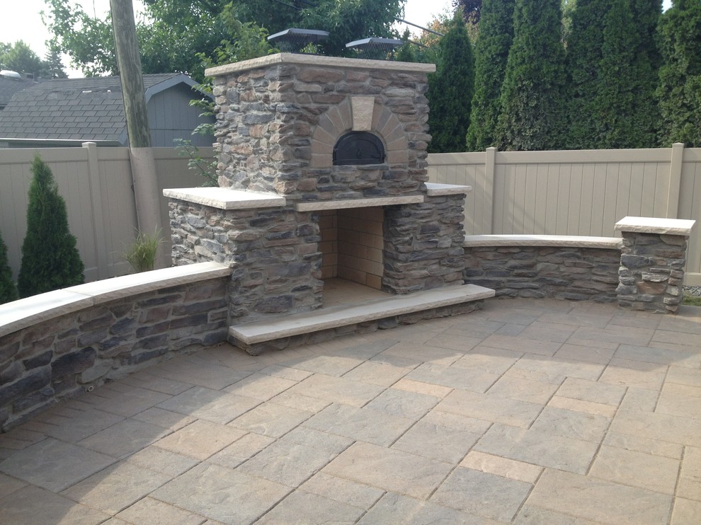 This is an example of a mediterranean back patio in Detroit with a fire feature and natural stone paving.