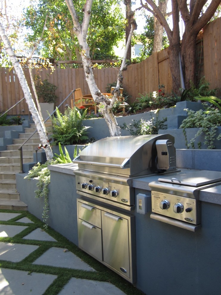 Cette image montre une terrasse arrière minimaliste de taille moyenne avec une cuisine d'été et des pavés en béton.