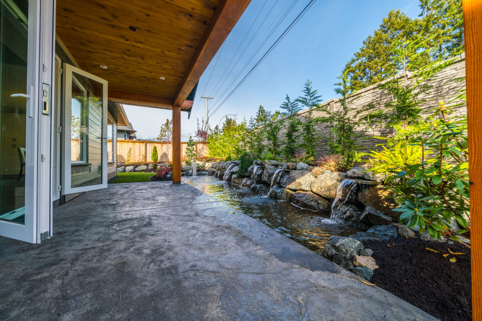 Überdachter Moderner Patio hinter dem Haus mit Wasserspiel und Stempelbeton in Vancouver