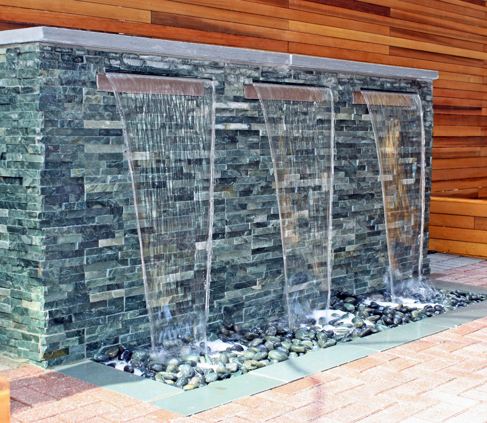 Cette image montre une terrasse design avec un point d'eau, une cour et des pavés en brique.