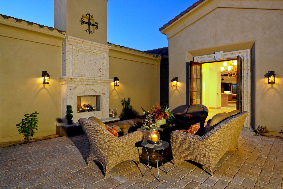 This is an example of a large traditional front patio in Phoenix with a fire feature, brick paving and no cover.