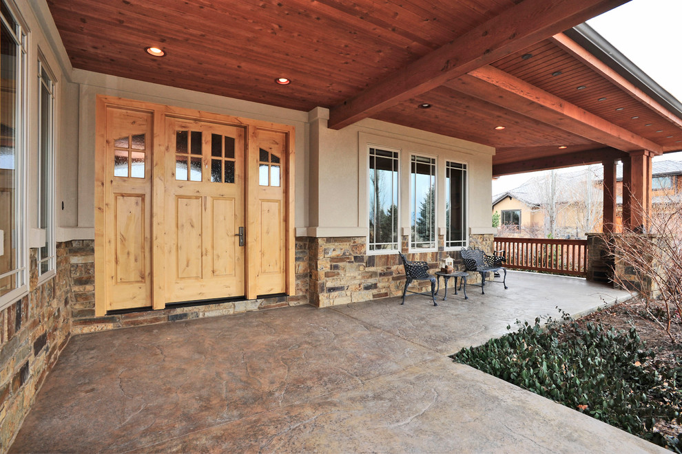 Large mountain style front yard stamped concrete patio photo in Denver with a roof extension