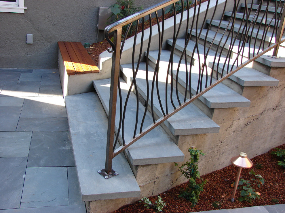 Example of a trendy limestone curved metal railing staircase design in San Francisco with concrete risers