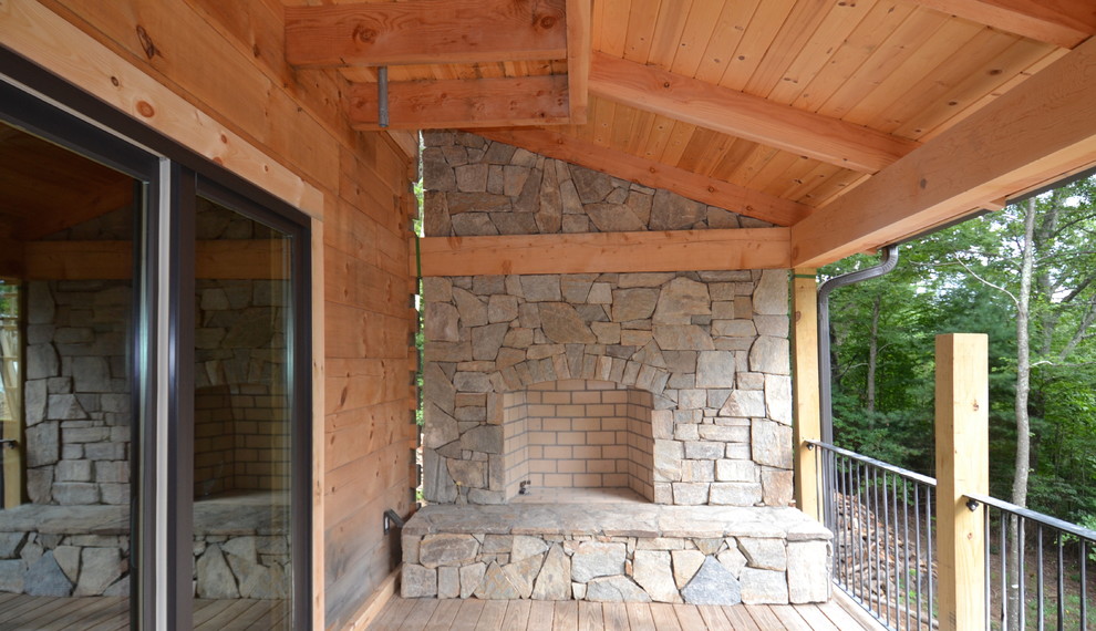 Cette photo montre une terrasse en bois arrière montagne de taille moyenne avec un foyer extérieur et une extension de toiture.