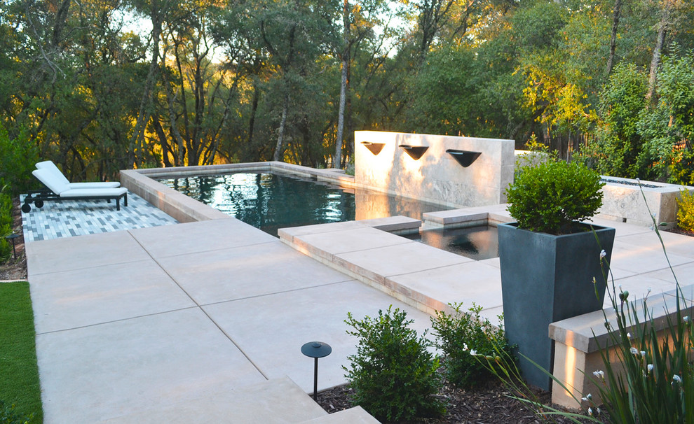 This is an example of a medium sized contemporary back patio in Sacramento with a water feature and stamped concrete.
