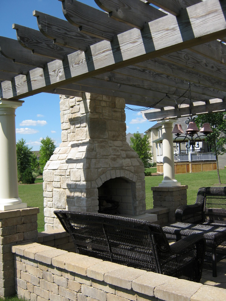 Foto di un patio o portico tradizionale dietro casa e di medie dimensioni con un focolare, pavimentazioni in pietra naturale e una pergola