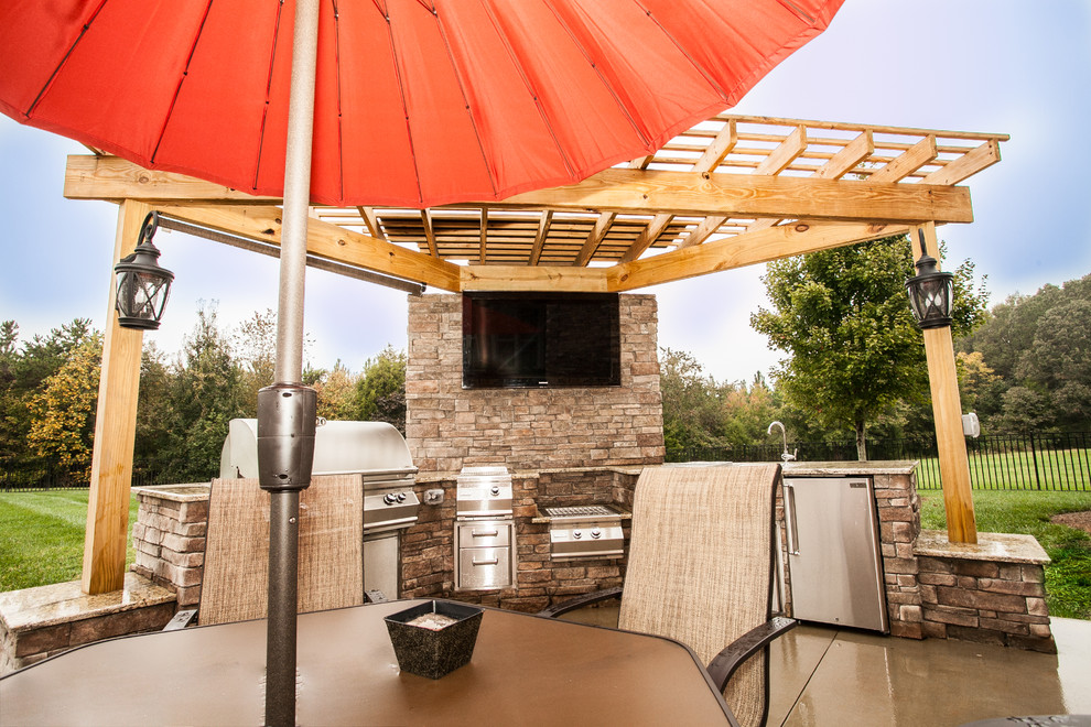 Photo of a medium sized traditional back patio in Charlotte with an outdoor kitchen, concrete slabs and a pergola.