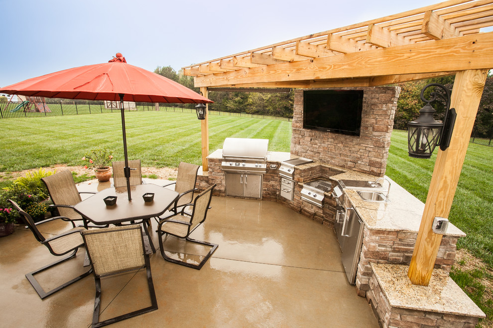 Cette photo montre une terrasse arrière craftsman de taille moyenne avec une cuisine d'été, une dalle de béton et une pergola.