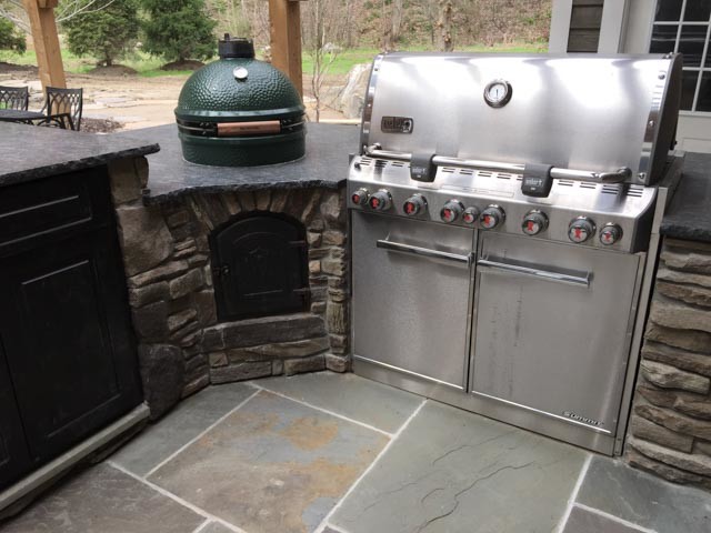 Cette photo montre une terrasse arrière chic de taille moyenne avec une cuisine d'été, des pavés en pierre naturelle et aucune couverture.