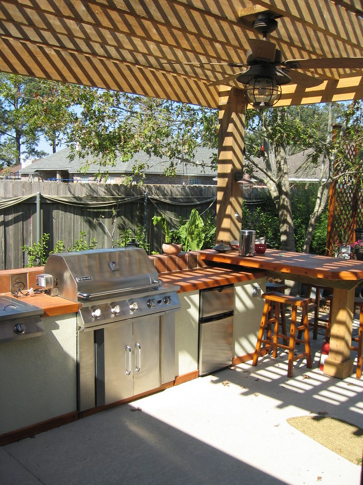 Mid-sized elegant backyard concrete patio kitchen photo in New Orleans with a pergola