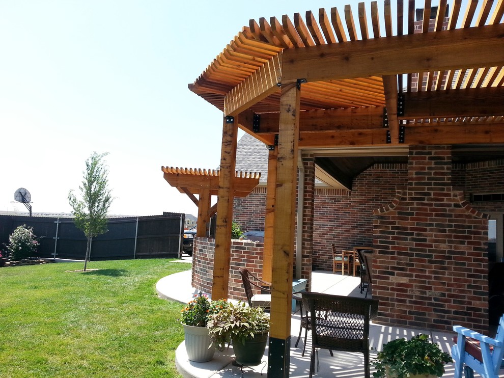 Foto de patio de estilo americano de tamaño medio en patio trasero con cocina exterior, losas de hormigón y pérgola