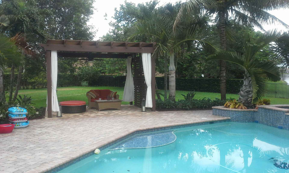 Bild på en mellanstor tropisk uteplats på baksidan av huset, med marksten i tegel och en pergola