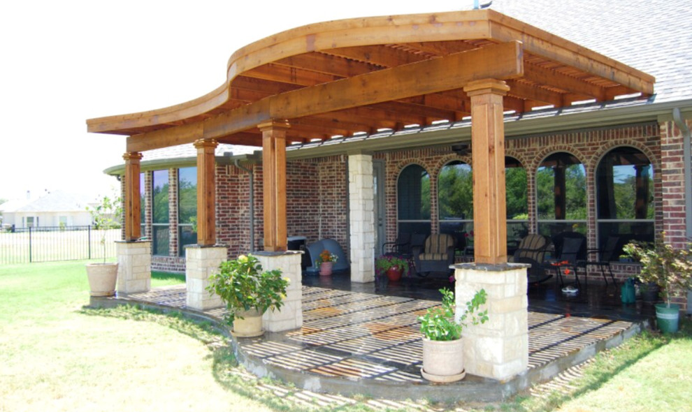 Photo of a large rustic back patio in Houston with stamped concrete and a pergola.
