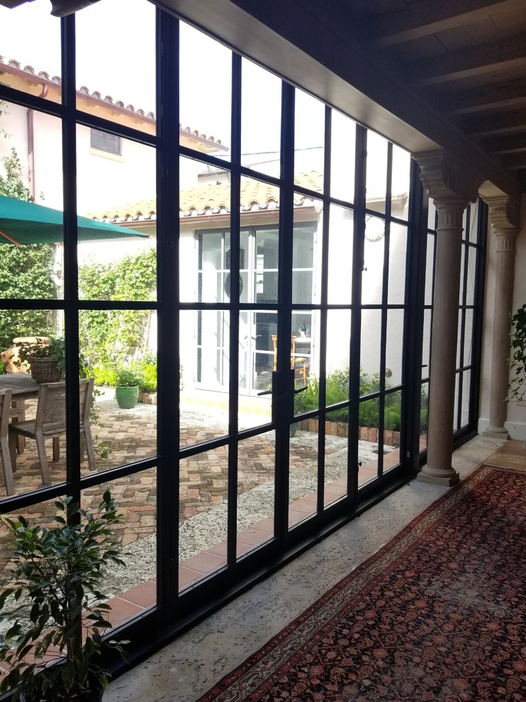 Esempio di un patio o portico mediterraneo di medie dimensioni e dietro casa con pavimentazioni in mattoni e nessuna copertura