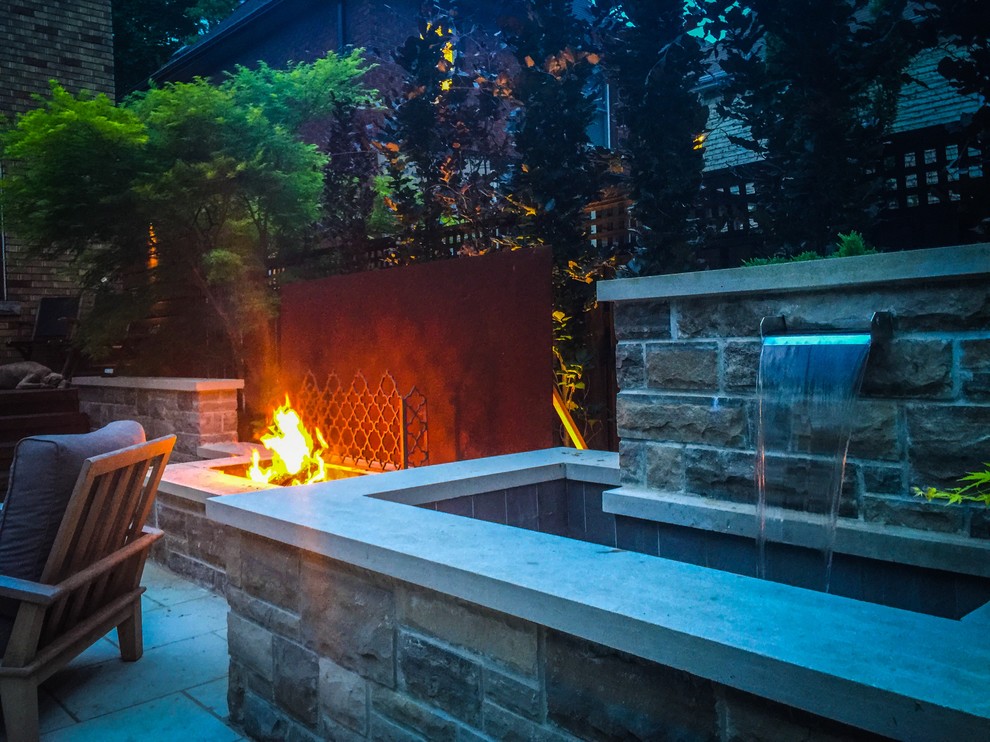 Small contemporary back patio in Toronto with a water feature, natural stone paving and no cover.