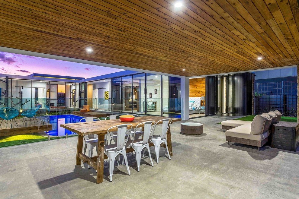 Example of a trendy backyard concrete patio design in Gold Coast - Tweed with a roof extension