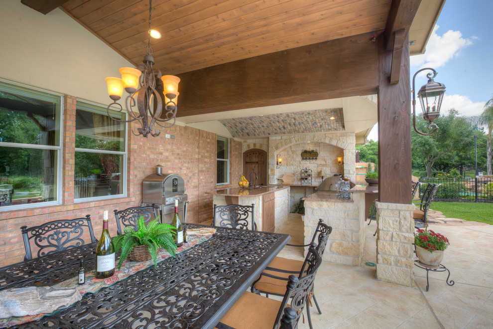 Photo of an expansive contemporary back patio in Houston with an outdoor kitchen, natural stone paving and a roof extension.