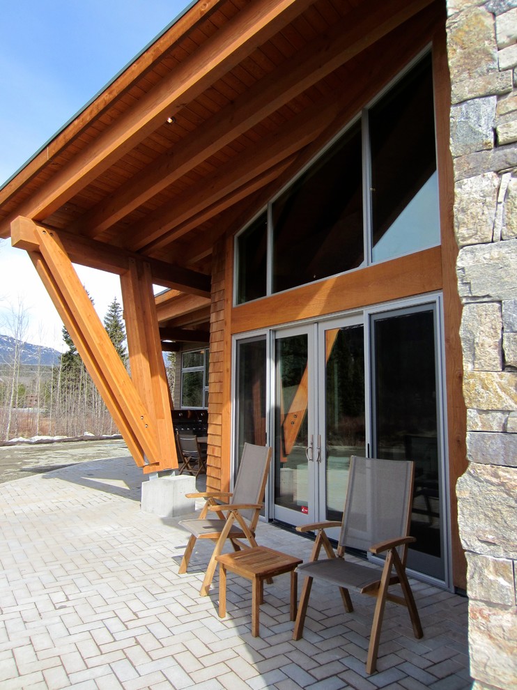 Réalisation d'une terrasse arrière design de taille moyenne avec des pavés en béton et une extension de toiture.