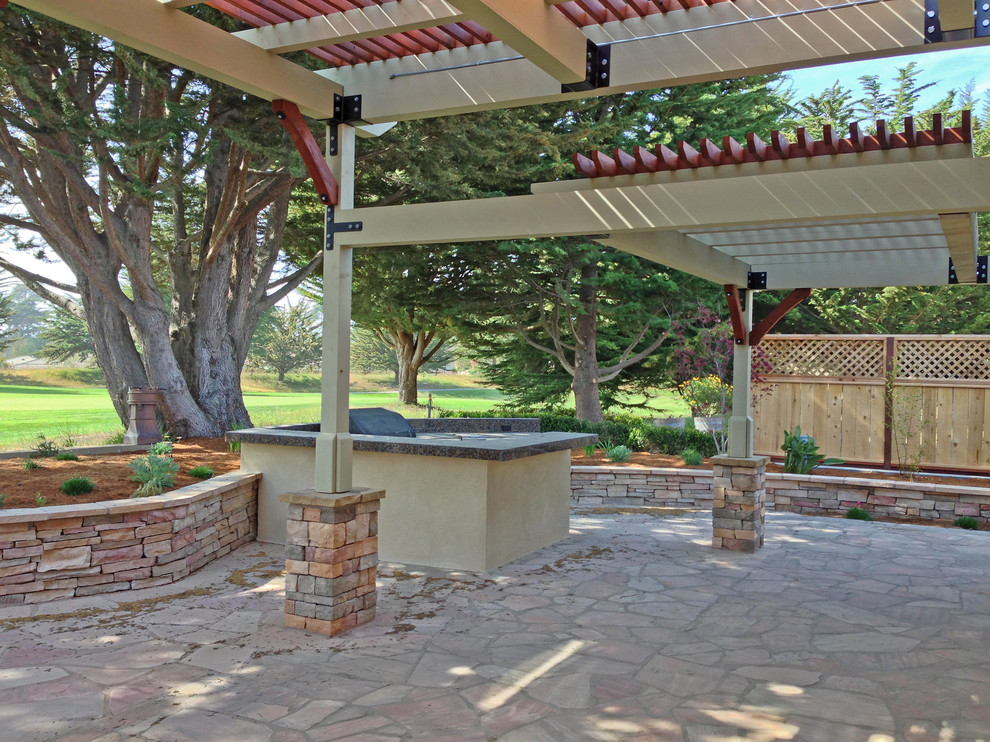 Ejemplo de patio tradicional de tamaño medio en patio trasero con cocina exterior, pérgola y adoquines de piedra natural