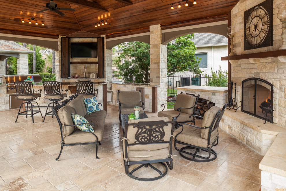 Immagine di un ampio patio o portico classico dietro casa con pavimentazioni in pietra naturale e un tetto a sbalzo