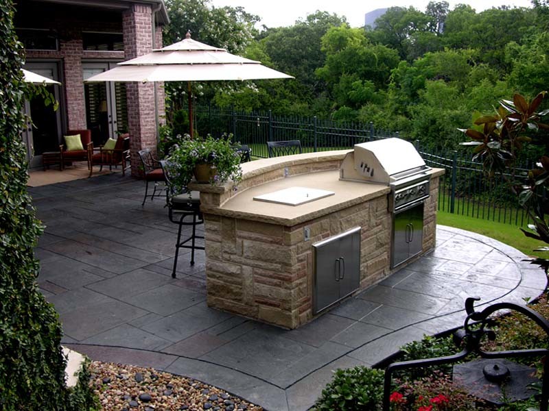 This is an example of a medium sized traditional back patio in Dallas with an outdoor kitchen, stamped concrete and no cover.