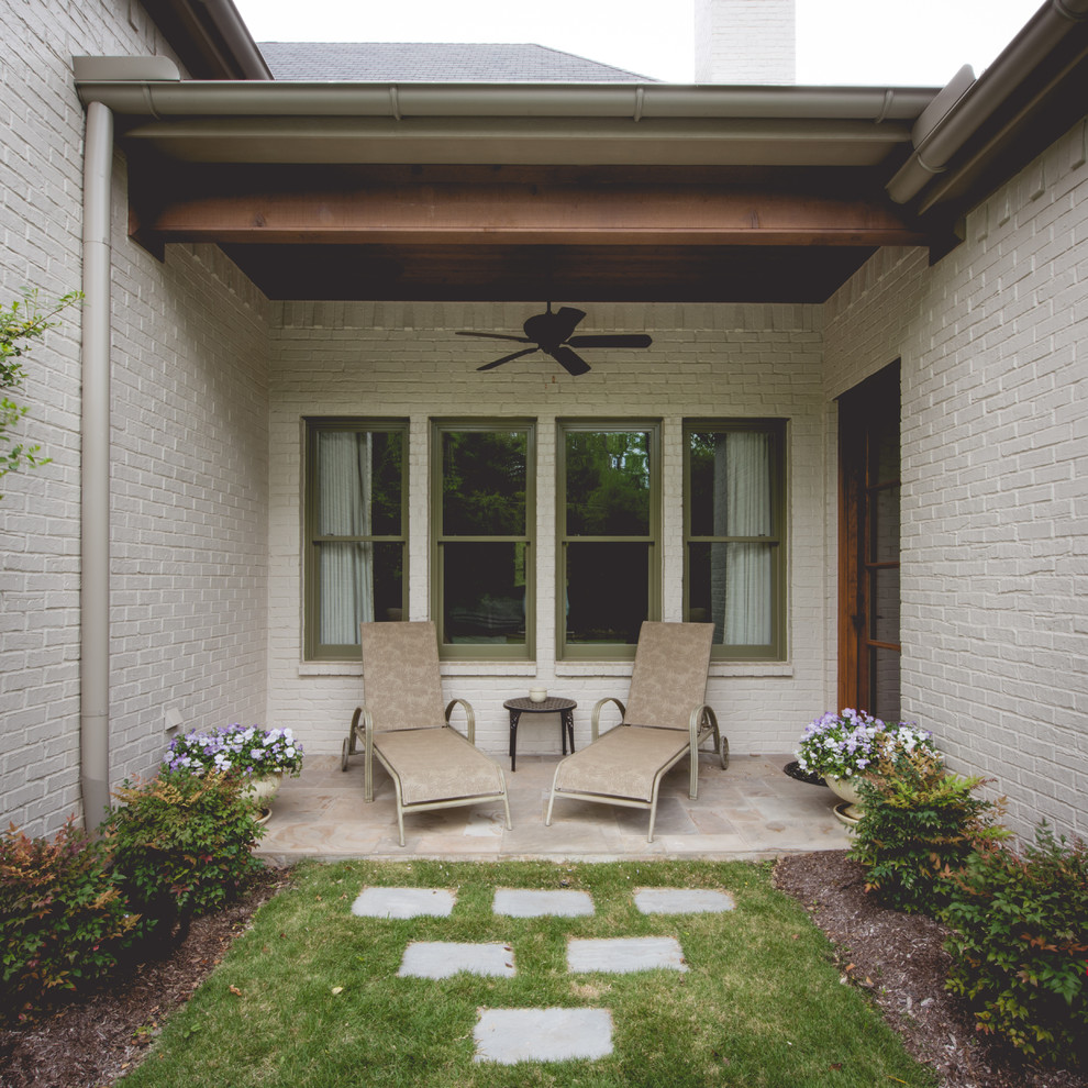 Foto di un piccolo patio o portico tradizionale dietro casa con pavimentazioni in pietra naturale e un tetto a sbalzo